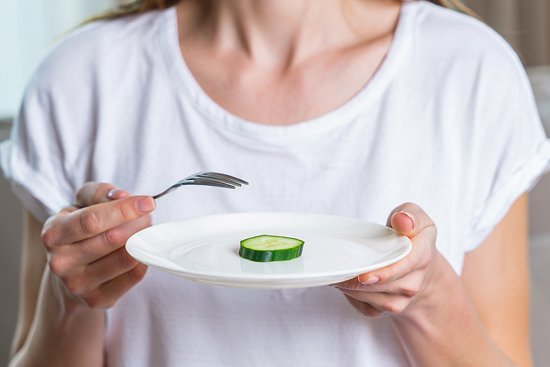 У девушки в руках тарелка с огурцом